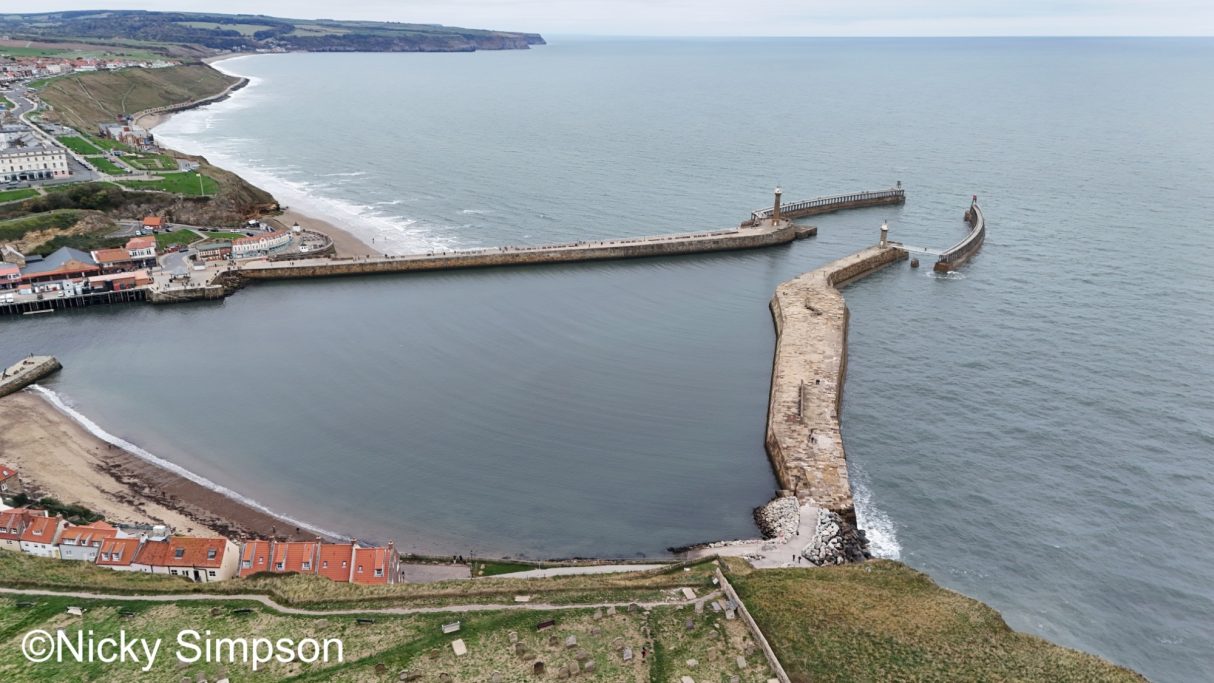 Aerial view of a coastal harbour with breakwaters and calm water.