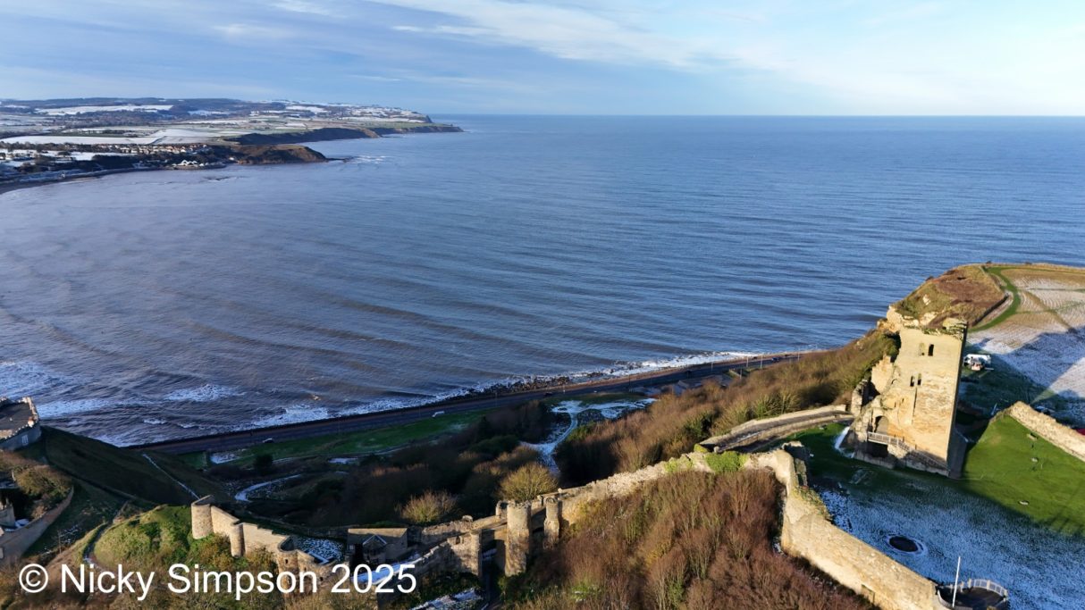 A coastal view featuring a fortress ruins and calm sea under a clear sky.