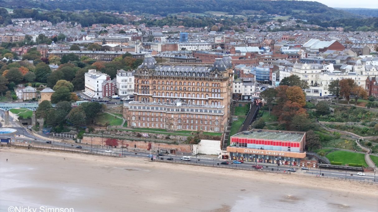 Coastal view featuring a large hotel and nearby beach with cloudy skies.
