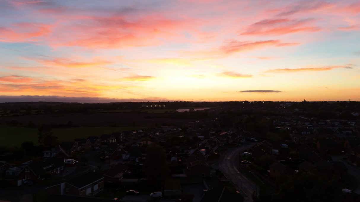 Sunset over a landscape, with vibrant pink and orange hues in the sky.